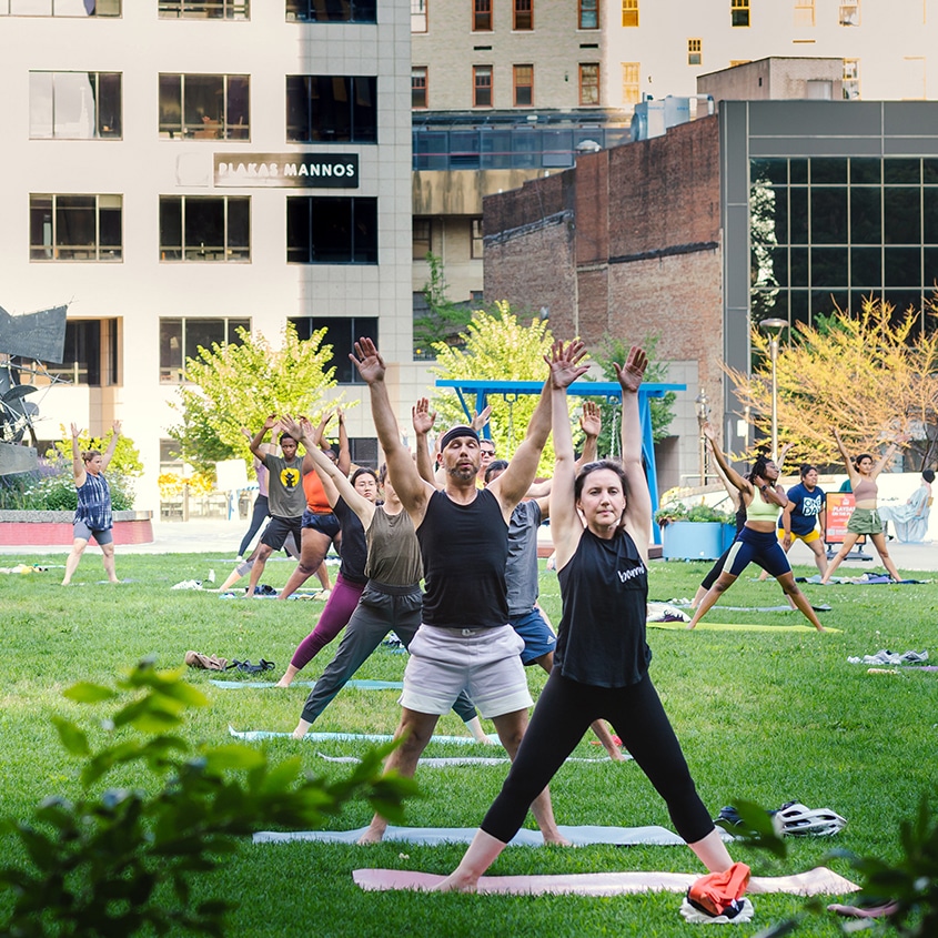 Photograph of a group of 20-30 people of different ages and ethnicities attending a free yoga class on Cascade Plaza in downtown Akron. Photo: Talia Hodge